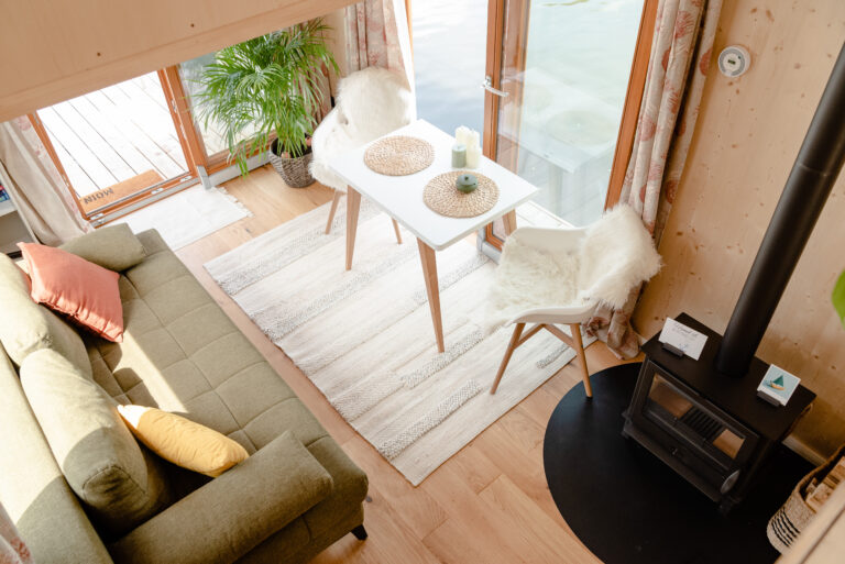 Der Wohnbereich des Hausbootes IRENE von der höher gelegenen Schlafebene aus gesehen. (Schlaf)Sofa, Sitzbereich, Kamin und tolle Ausblicke.