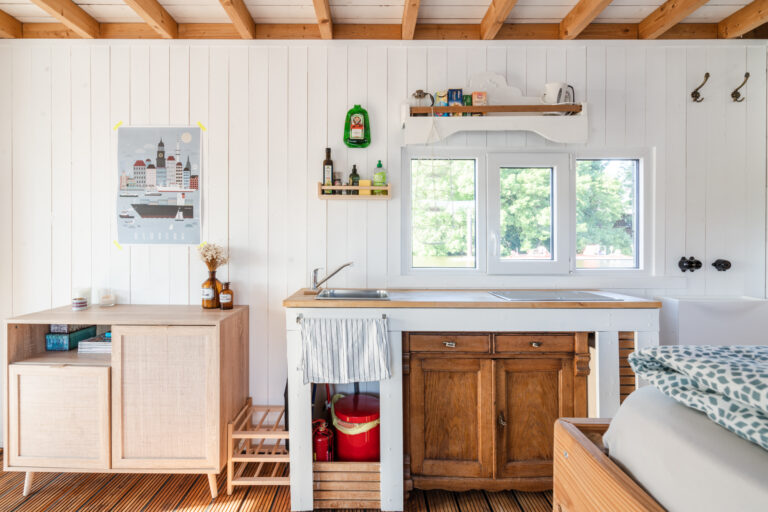 Hauptraum des Hausbootes WILMA mit Bett (rechts) und Küchenzeile. Beim Kochen könnt ihr übers Wasser blicken.