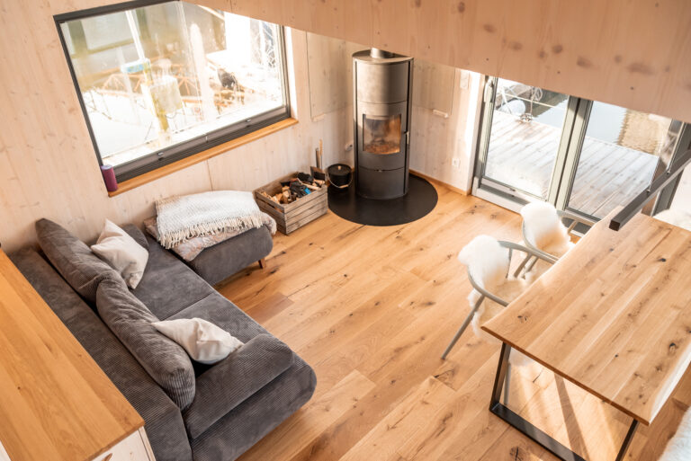 Der Wohnbereich: (Schlaf)Sofa, Holzofen, gemütlicher Sitzbereich am Tisch mit Ausblick übers Wasser